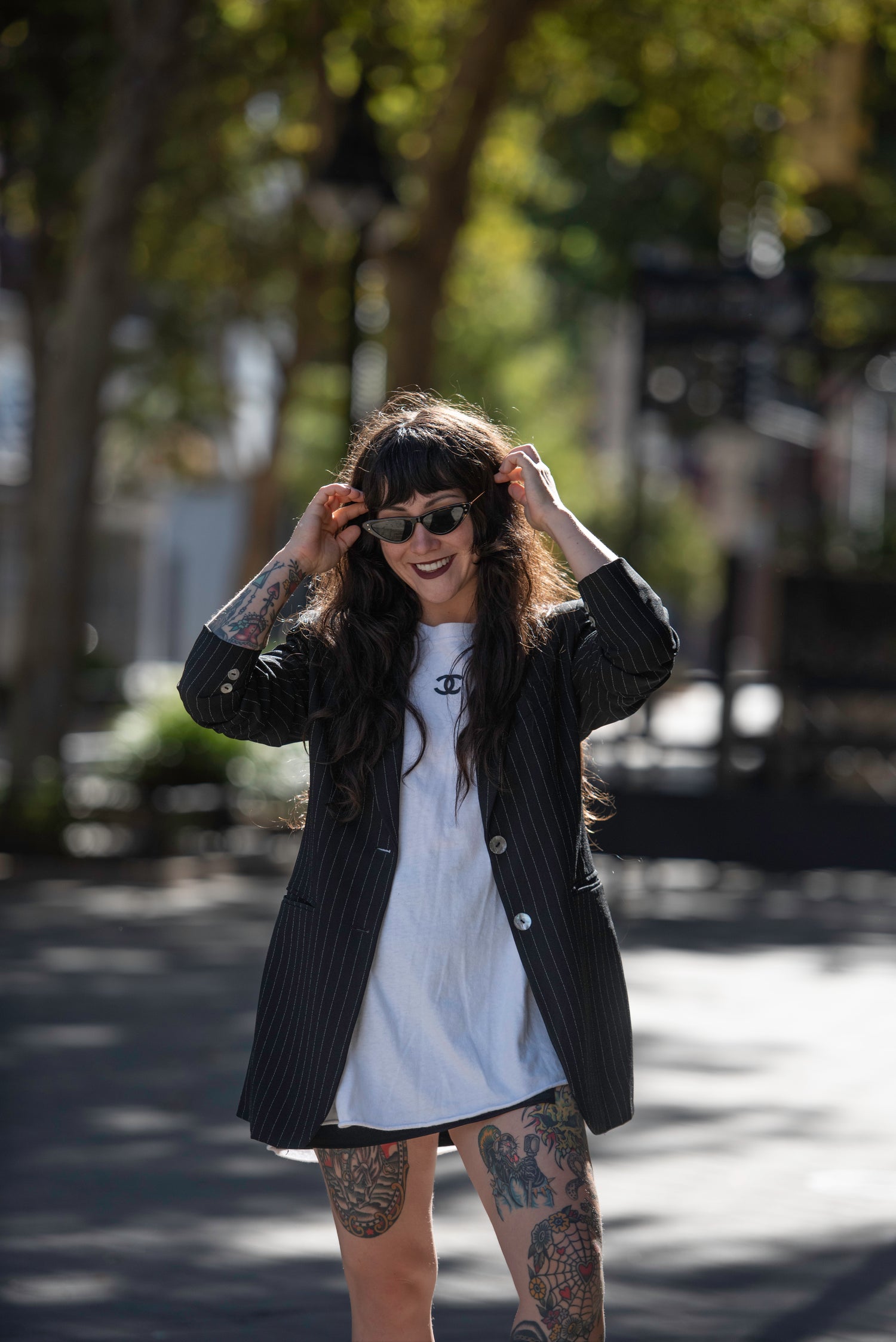 Old Moon Vintage adjusting vintage cateye sunglasses in a Chanel t-shirt and pinstripe blazer